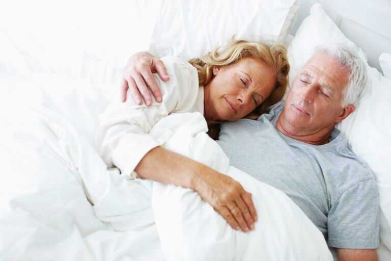 Man en vrouw die samen liggen te slapen. De vrouw ligt op de borst van de man en de man heeft zijn arm om haar heen.