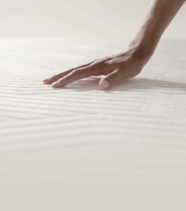 Een hand die op een TEMPUR®-matras drukt en de terugvering van de matras laat zien